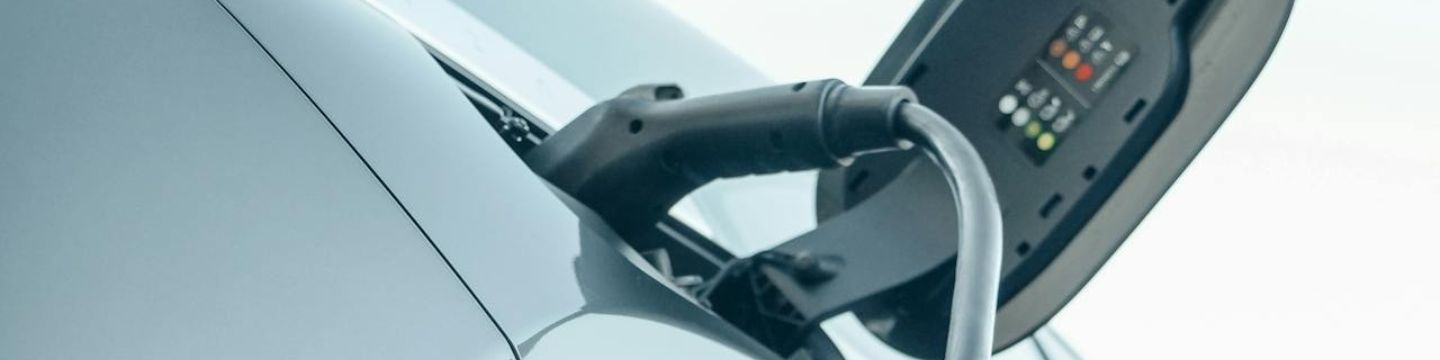 Macchine elettriche_websim2 Veicolo elettrico in ricarica presso una colonnina moderna, simbolo di mobilità sostenibile e tecnologie pulite.