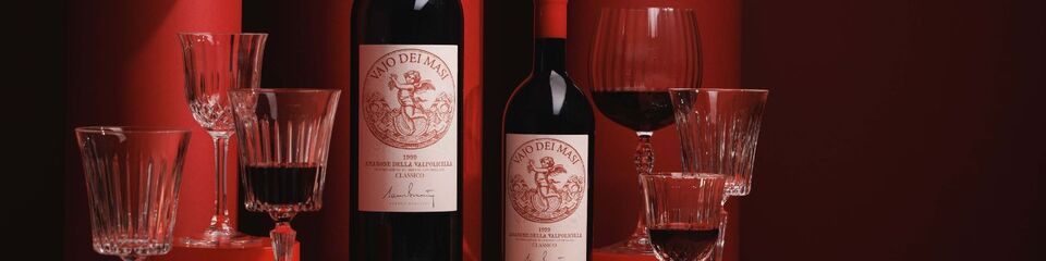 Sfondo rosso drappeggiante, in primo piano i calici e i vini di Masi Agricola