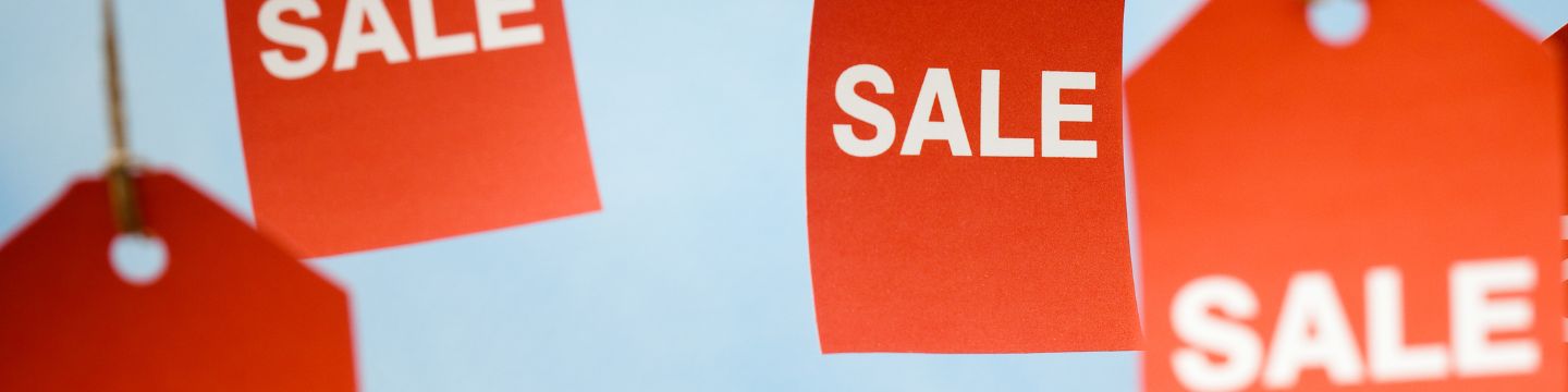 sales_websim Immagine rappresentativa di cartellini rossi che penzolano dal soffitto con il testo "Sale" in primo piano di colore bianco