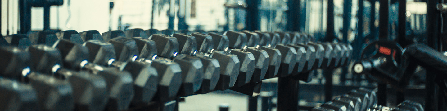 Atleta solleva manubri in palestra: Uomo concentrato durante una sessione di allenamento con pesi.