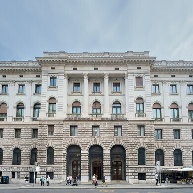 Trieste, 27 giugno 2024. Storico edificio monumentale bianco di Intesa Sanpaolo in Via Mazzini, con passanti in strada.