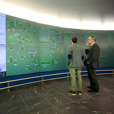Interno del Centro di Dispacciamento Snam, con operatori davanti a schermi e pannelli di controllo della rete gas.