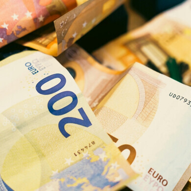 Insieme di banconote e monete in euro di diverso taglio disposte su una superficie, a rappresentare la valuta europea.