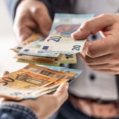 Primo piano delle mani di un uomo d’affari che scambiano banconote in euro.