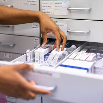 Primo piano di una farmacista che cerca medicinali su uno scaffale.