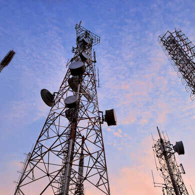 Fotografia di torri elettriche in acciaio con linee ad alta tensione visibili, su sfondo naturale o urbano.