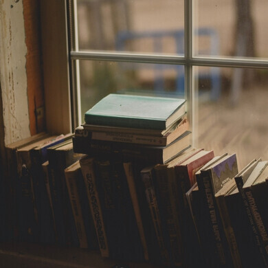 Libri antichi disposti su un davanzale di legno, con luce naturale che illumina le copertine