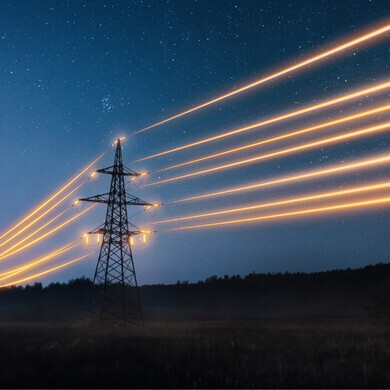 Tralicci dell’alta tensione illuminati da luci notturne su un paesaggio urbano o rurale