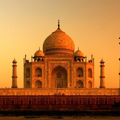 Taj Mahal visto di fronte, con il mausoleo bianco illuminato dai colori del tramonto