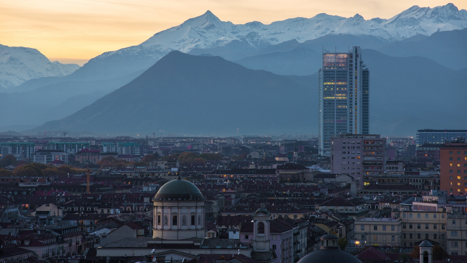Veduta aerea di tramonto di Torino Vista dall’alto di Torino con la cupola della Chiesa di San Massimo, il grattacielo Grattacielo Intesa Sanpaolo e le Alpi innevate sullo sfondo.