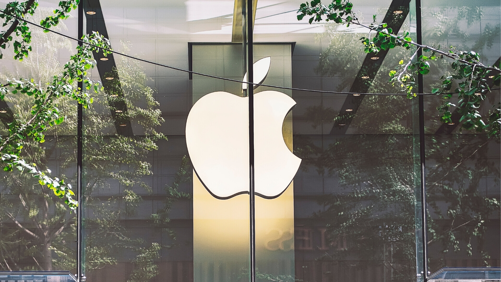 Logo Apple bianco e illuminato all’interno di uno spazio architettonico