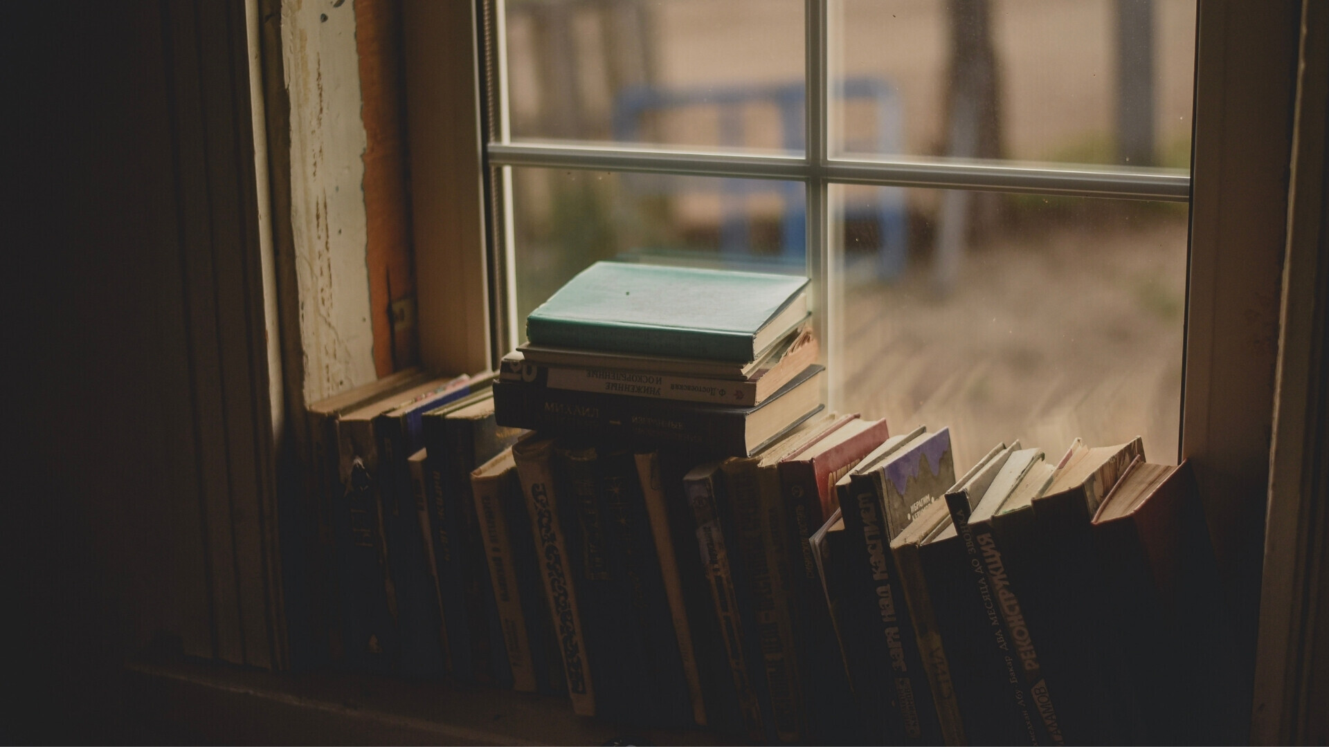 Libri antichi disposti su un davanzale di legno, con luce naturale che illumina le copertine