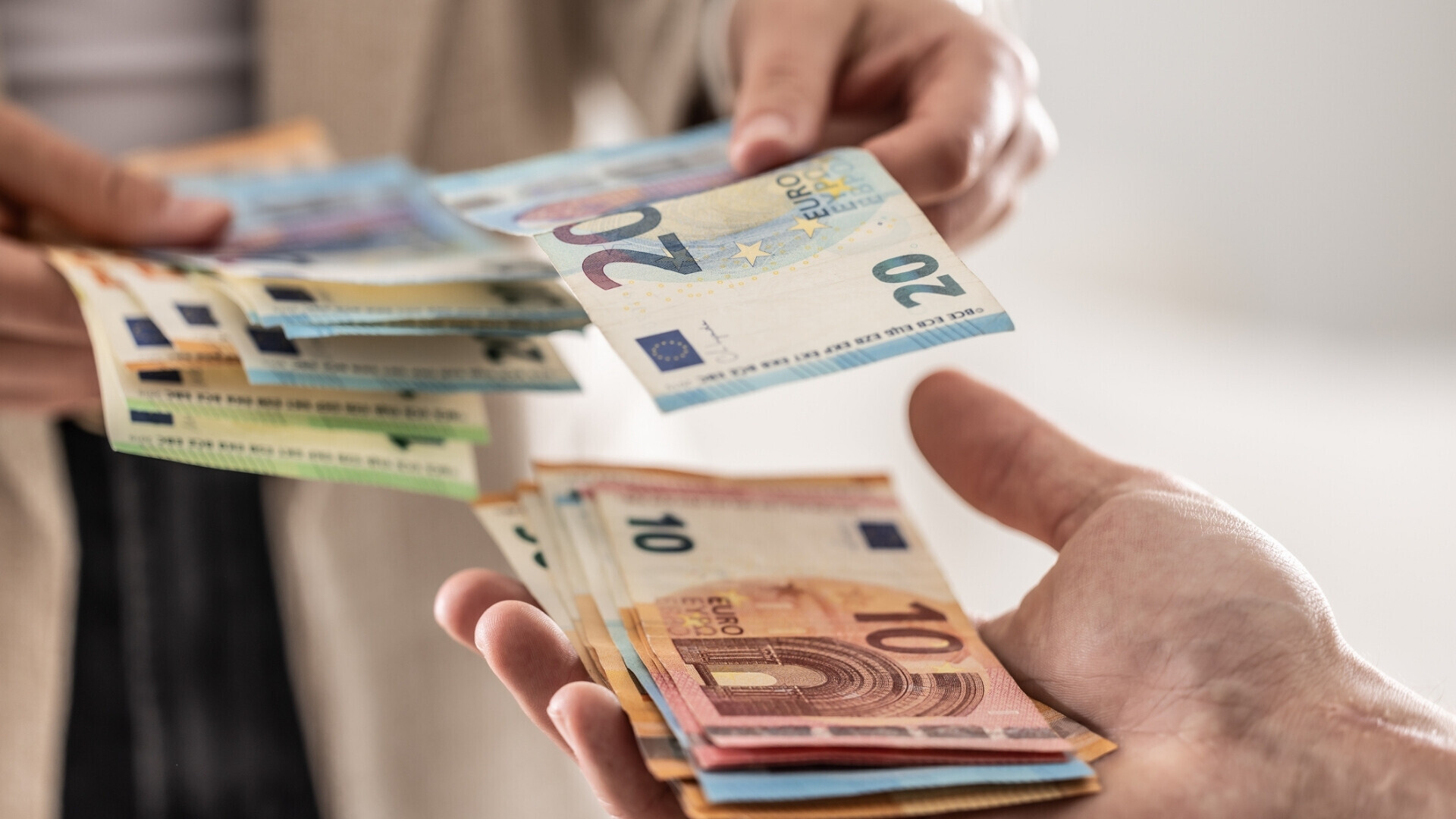 Mani di donna d'affari che si scambiano banconote in euro, primo piano Primo piano delle mani di una donna d’affari che scambiano banconote in euro, rappresentazione di transazioni finanziarie o pagamenti.