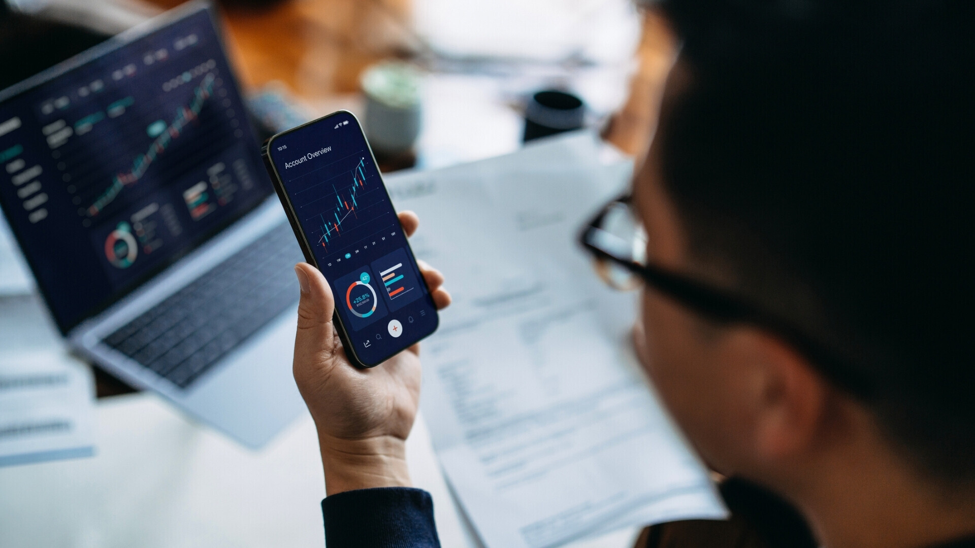 Giovane uomo asiatico gestisce finanze e investimenti online, analizzando operazioni in borsa con smartphone e laptop. Pianificazione finanziaria, banca e finanza, trading e mobile banking Giovane uomo asiatico analizza operazioni di borsa con smartphone e laptop, pianificando investimenti e attività finanziarie online.