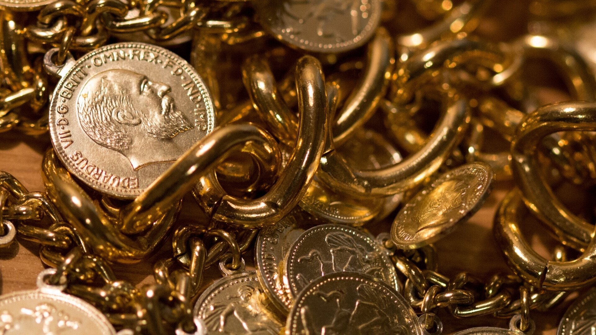 Gioielli e monete d'oro Gioielli e monete d’oro disposti insieme su una superficie lucida