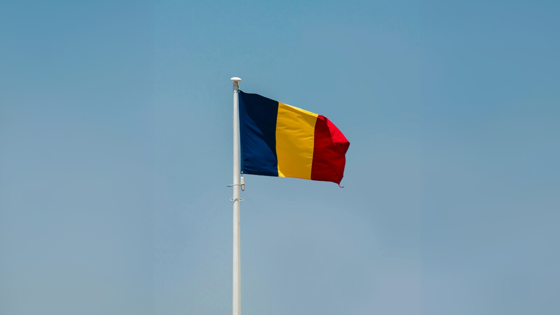 Bandiera tricolore della Romania che ondeggia sopra edifici o paesaggio