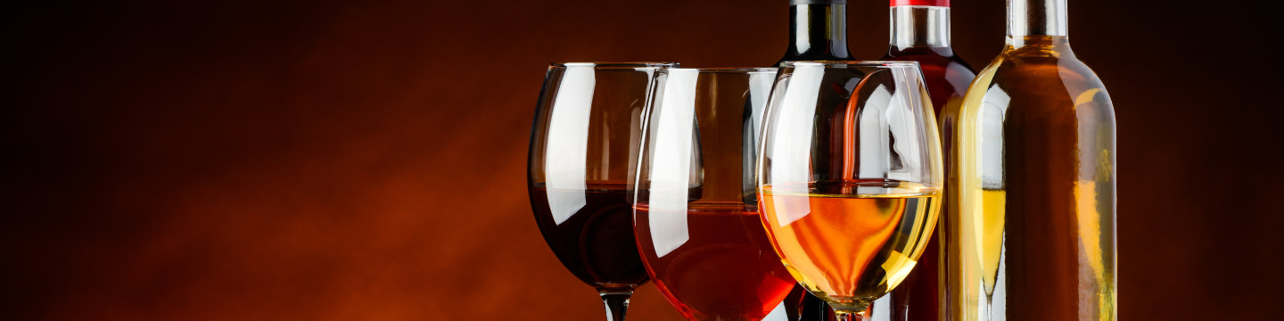 Calici riempiti di vino rosso e bianco su una tavola rustica